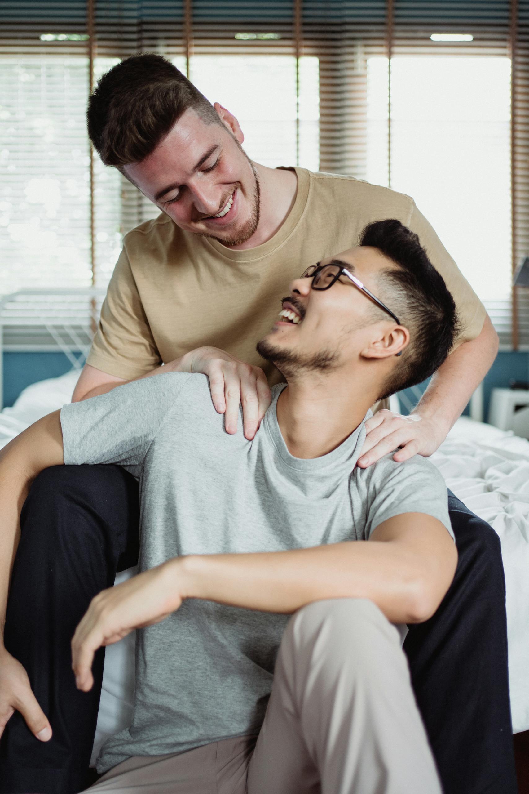 A loving interracial gay couple sharing a joyful moment indoors, looking at each other.