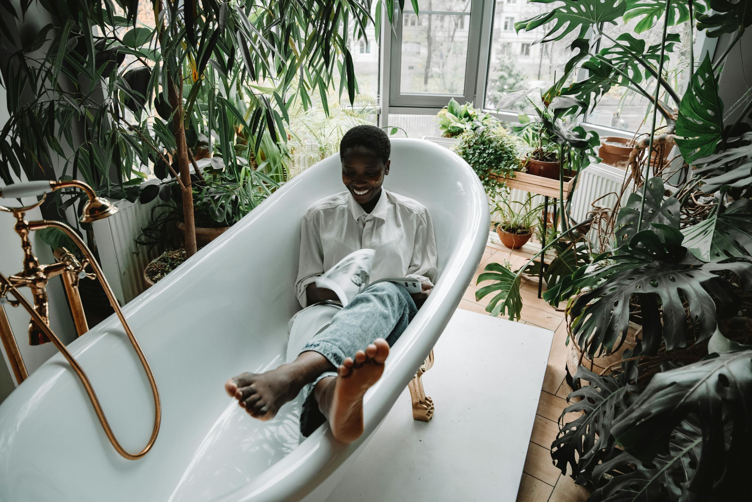 Content woman enjoying self-care in a bathtub, surrounded by lush indoor plants, embracing relaxation.